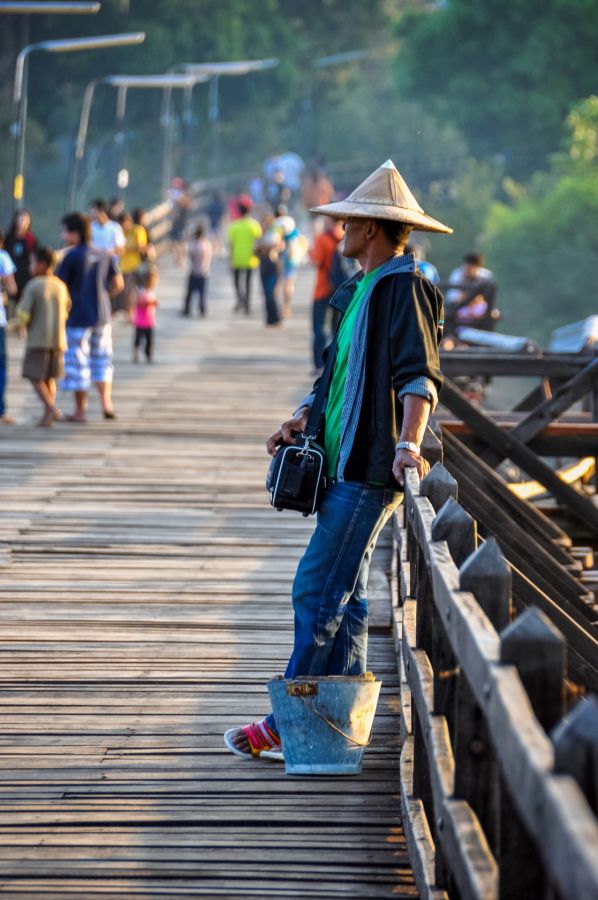 Homme au chapeau conique sur une passerelle animée
