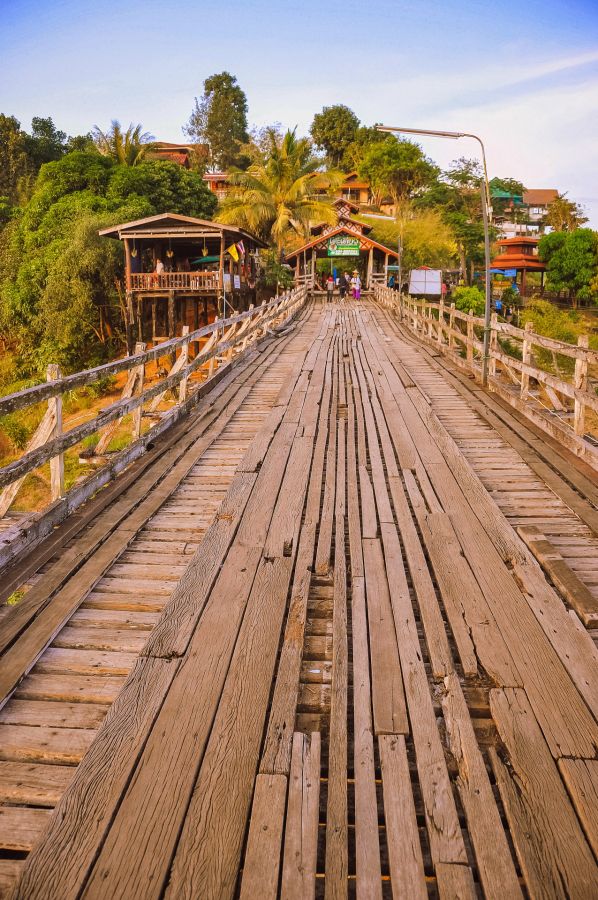Pont en bois menant à un village tropical verdoyant