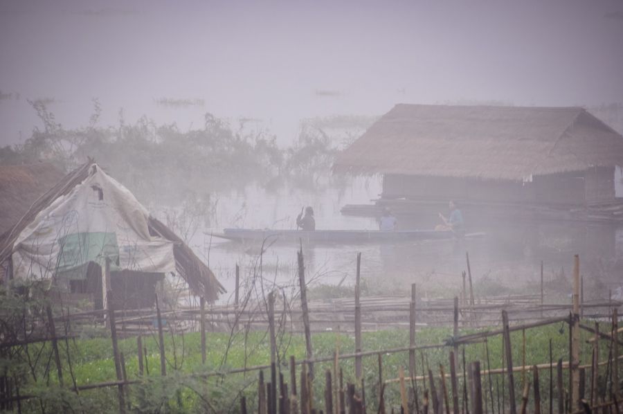 Pirogue devant des huttes sous une forte pluie
