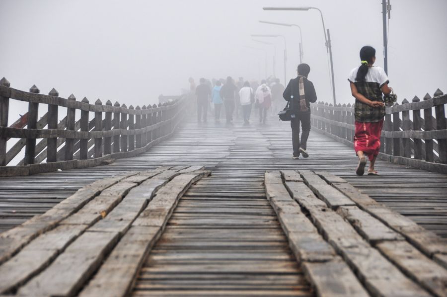 Piétons traversant un pont en bois dans le brouillard