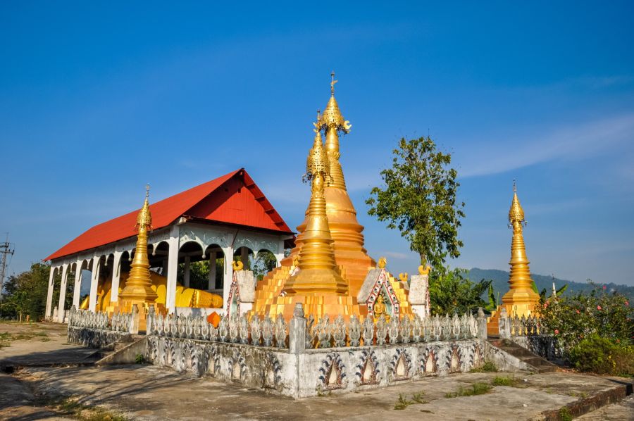 Pagode bouddhiste dorée devant un temple au toit rouge