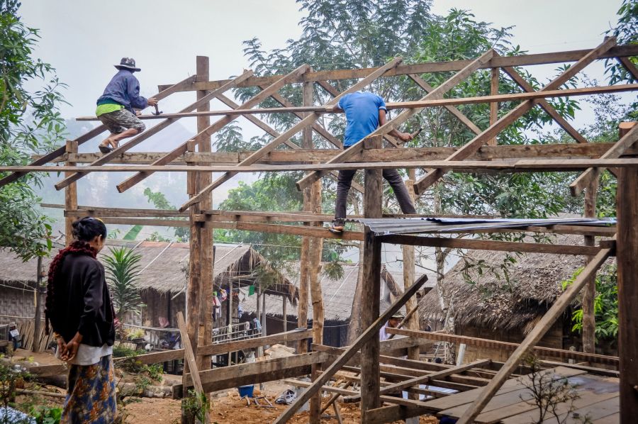 Ouvriers construisant une charpente en bois dans un village rural