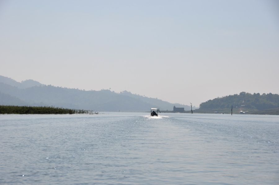 Bateau naviguant sur un lac bordé de collines brumeuses