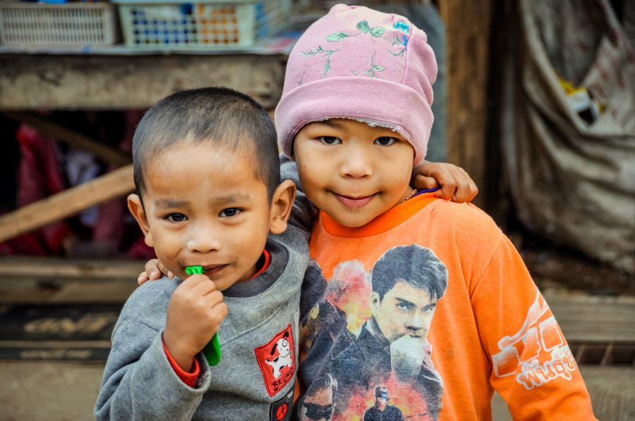 Deux jeunes enfants souriants, l’un portant un bonnet rose