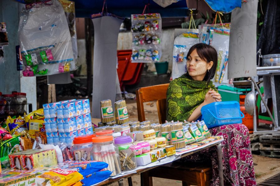 Marchande assise derrière un étal de produits variés