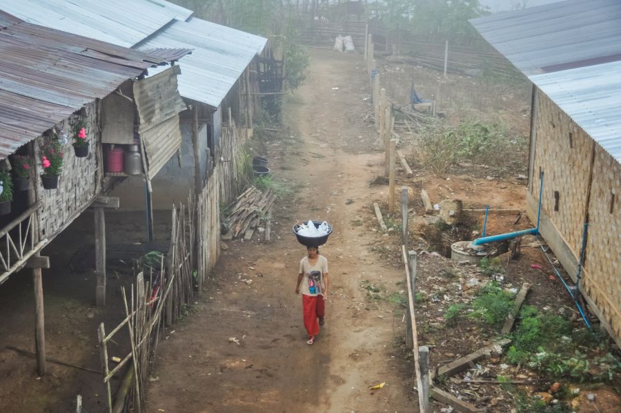 Femme portant une bassine dans un village rural brumeux