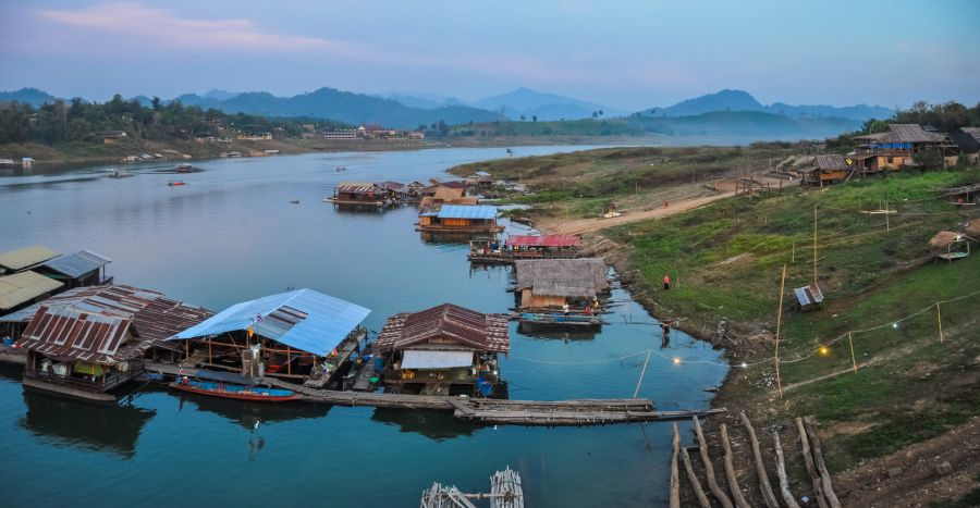 Maisons flottantes sur un lac entouré de montagnes brumeuses
