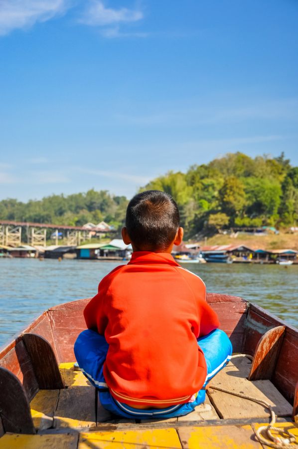 Enfant en veste rouge assis dans une barque