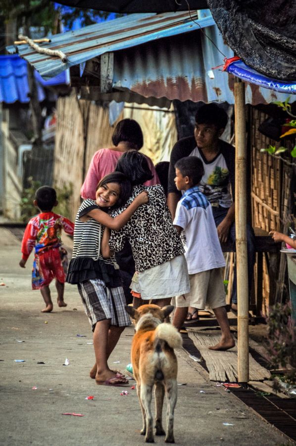 Enfants souriants dans une ruelle, avec un chien au premier plan