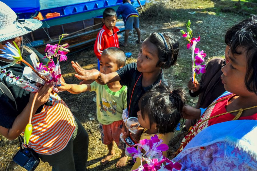 Enfants et femmes offrant des fleurs près de bateaux