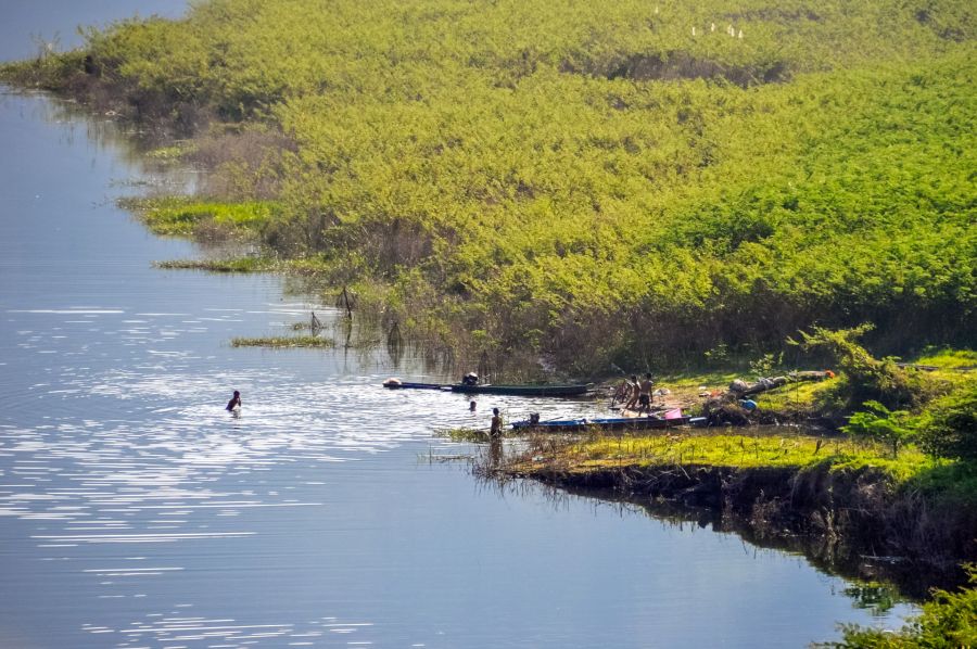 Pêcheurs et baigneurs au bord d’une rivière verdoyante