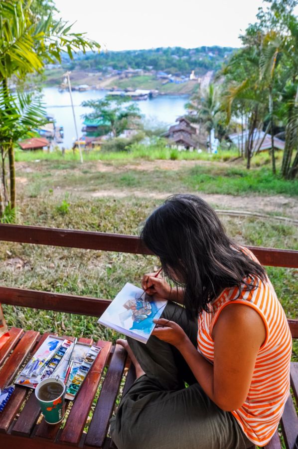 Femme peignant au bord d’un lac tropical