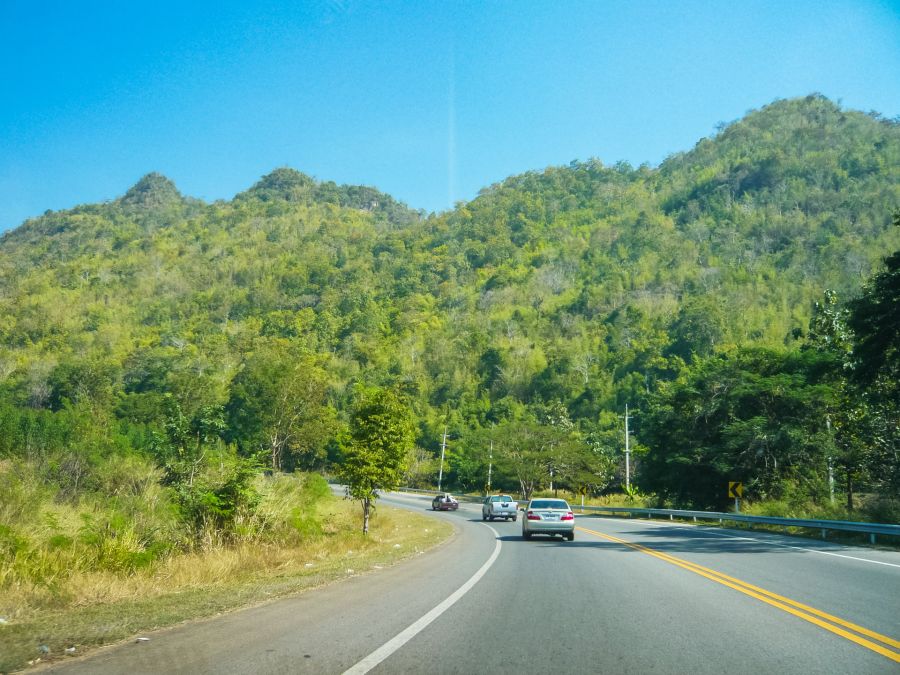 Route sinueuse traversant des collines verdoyantes sous ciel bleu