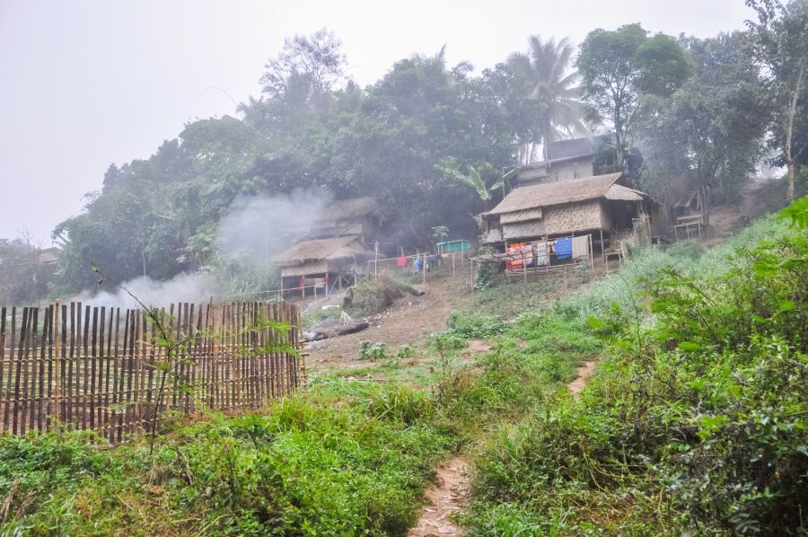 Maisons en bambou fumantes dans un village tropical verdoyant