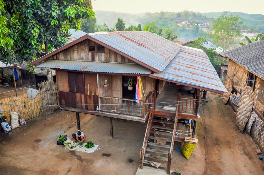 Maison sur pilotis en bois dans un village verdoyant