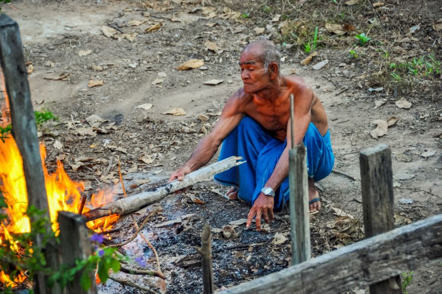 Homme alimentant un feu de bois en extérieur