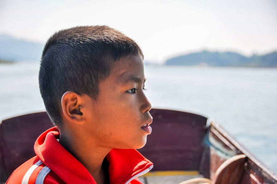 Garçon en gilet rouge assis dans un bateau