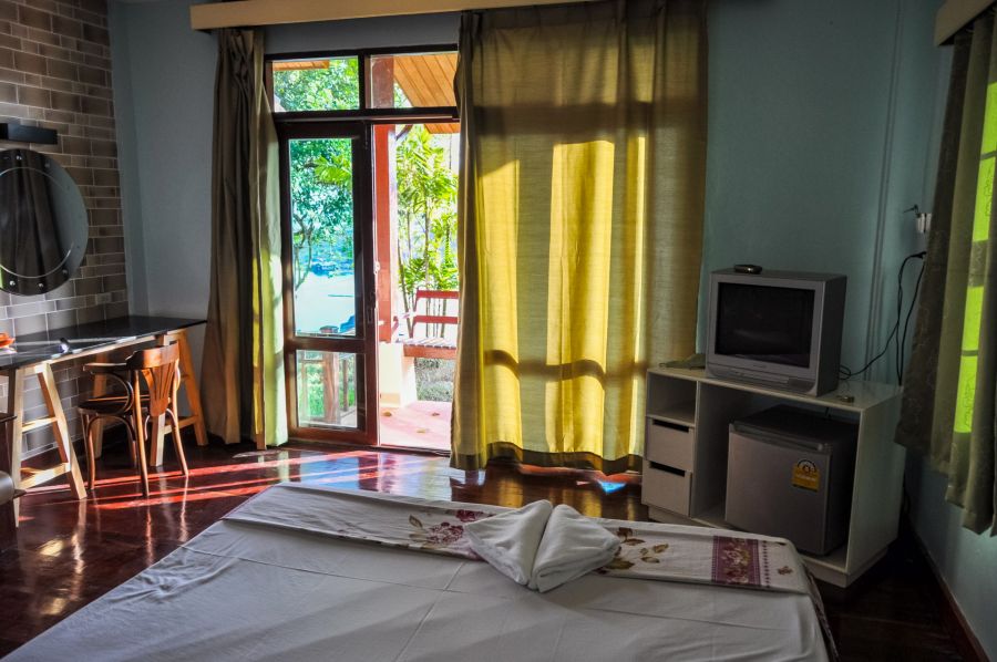 Chambre avec lit, télévision et balcon donnant sur jardin