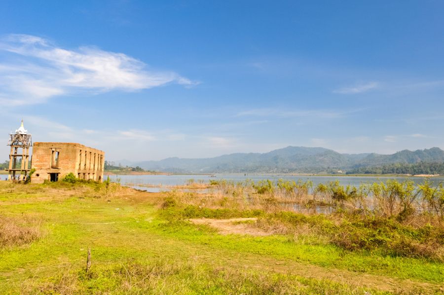 Bâtiment abandonné au bord d’un lac entouré de collines