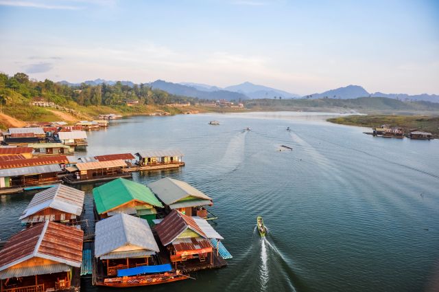 Village flottant sur lac, bateau et montagnes brumeuses