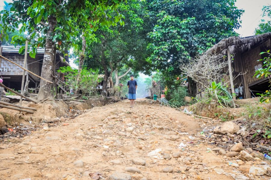 Jeune homme sur chemin rural entre maisons en bambou
