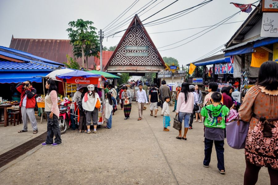 Marché animé devant une porte traditionnelle en Thaïlande