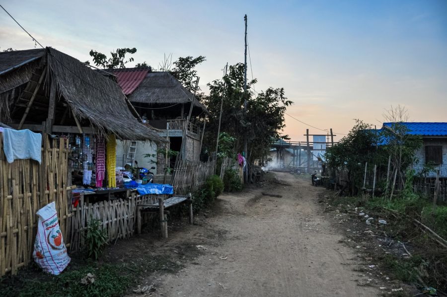 Ruelle en terre entre maisons rurales en bambou au crépuscule