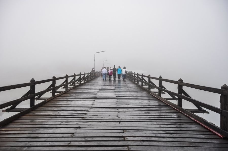 Personnes marchant sur une jetée en bois dans le brouillard