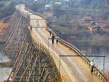 Long pont en bambou traversant une rivière près de maisons