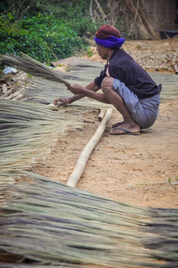 Artisan assemblant des fibres végétales sur des tiges de bambou