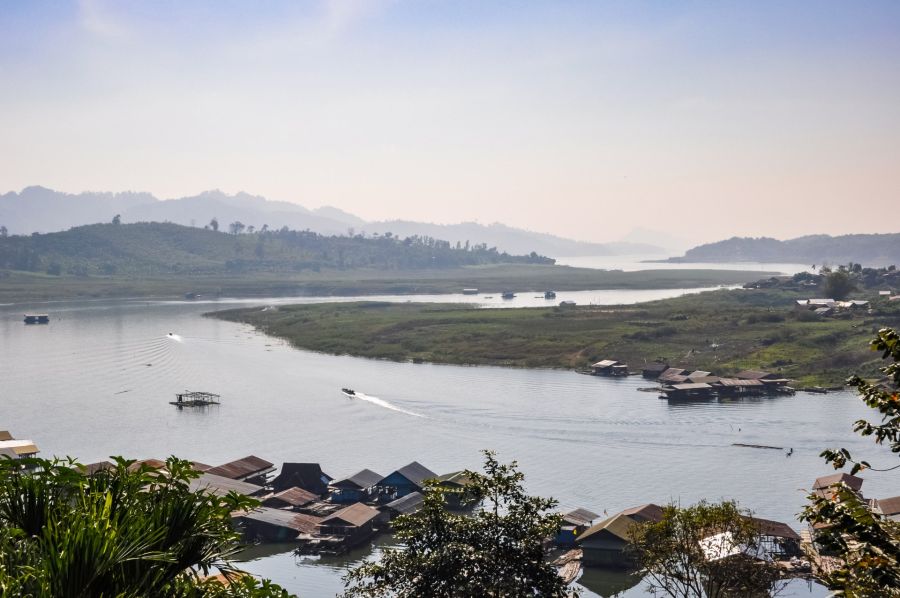 Village flottant sur rivière bordée de collines brumeuses