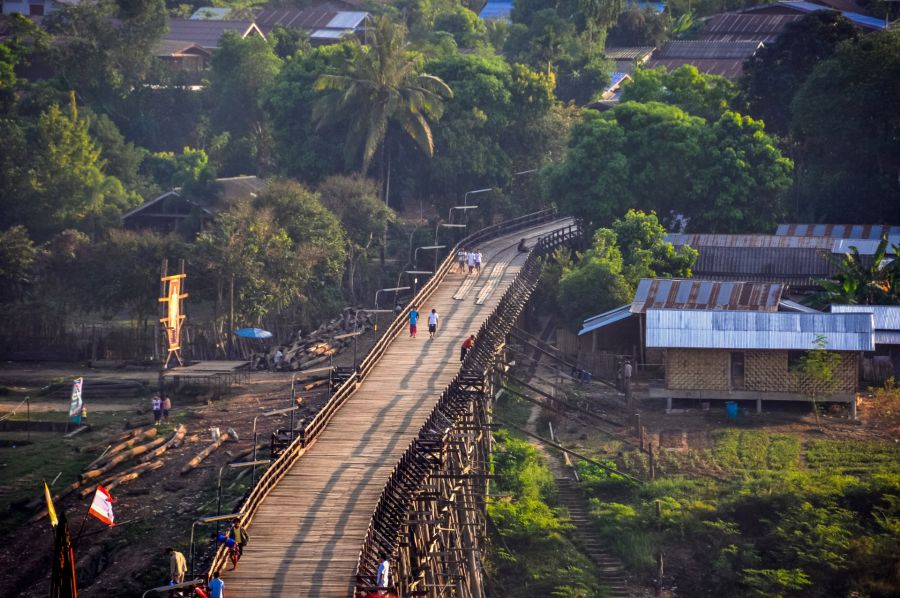 Passerelle en bois traversant un village tropical verdoyant