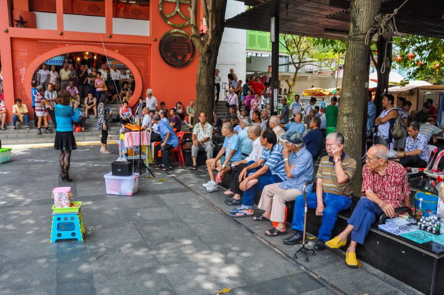 Personnes âgées réunies devant un bâtiment asiatique coloré