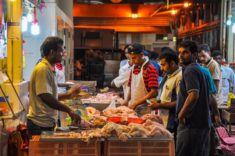Clients devant un étal de poulet cru au marché