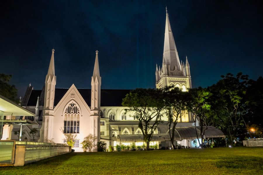 Église néogothique illuminée la nuit, avec haut clocher
