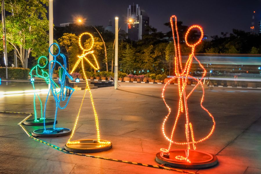 Sculptures lumineuses de musiciens dans une rue nocturne