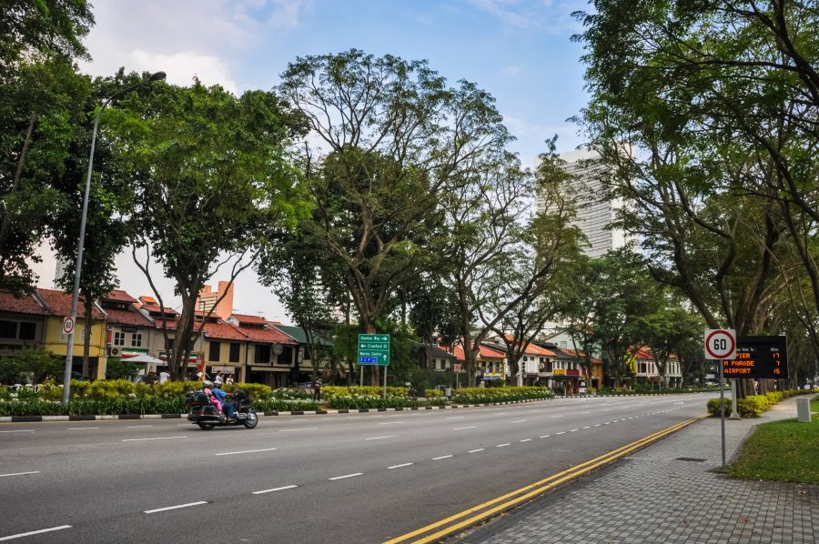 Rue arborée de Singapour avec moto et maisons traditionnelles