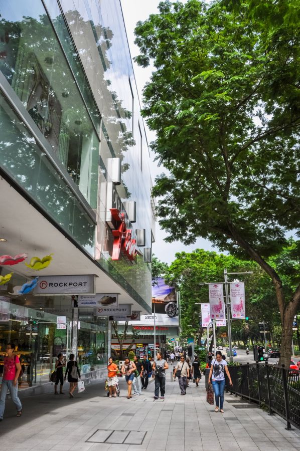 Passants devant commerces d’Orchard Road bordée d’arbres