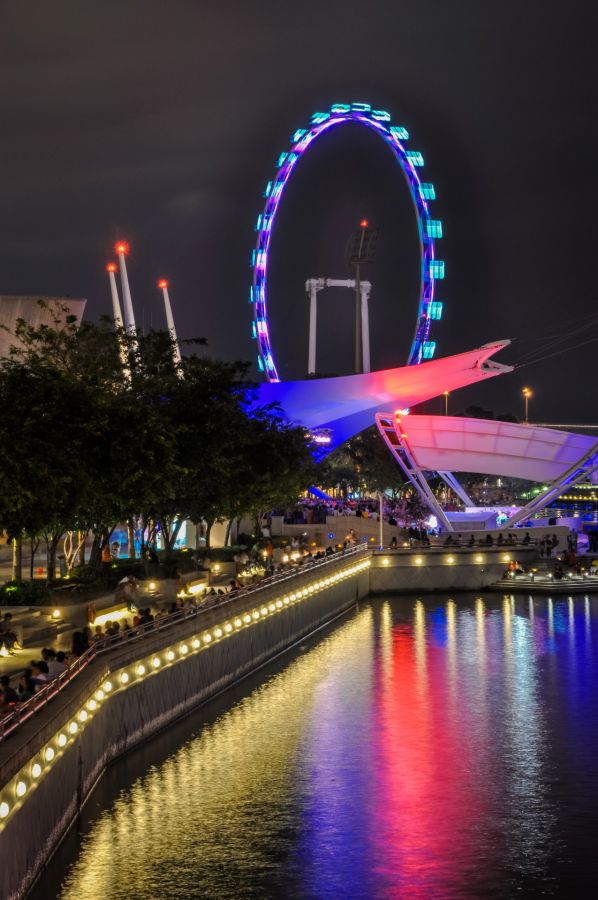 Grande roue illuminée au bord d’un canal nocturne