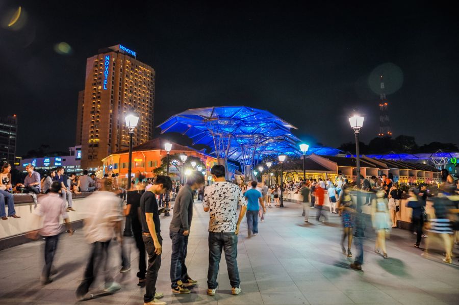 Foule nocturne devant le Novotel et une canopée bleue