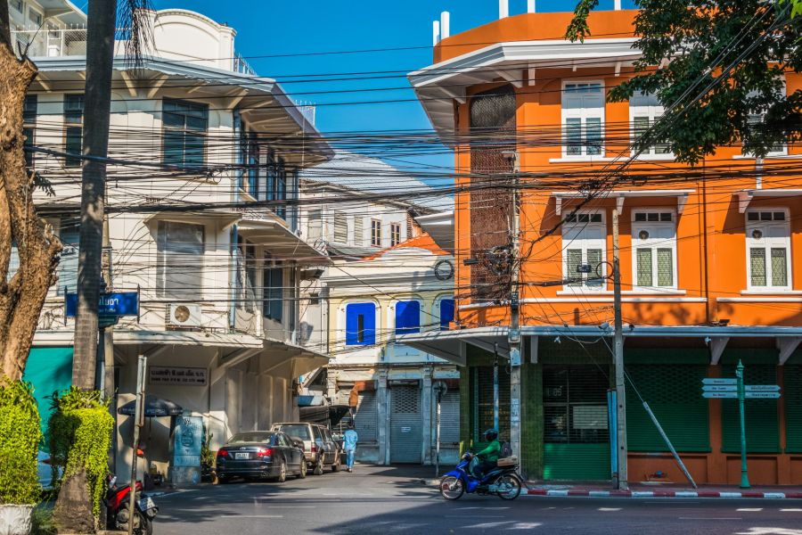 Rue urbaine thaïlandaise avec immeubles colorés et câbles électriques