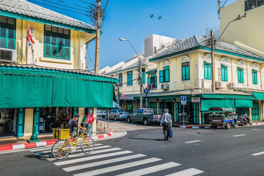 Rue de Bangkok avec cycliste, tuk-tuk et façades colorées