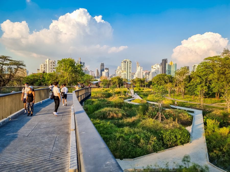 Promeneurs sur une passerelle, parc urbain et gratte-ciel