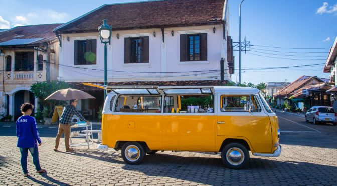 van jaune sur une place de savannakhet laos