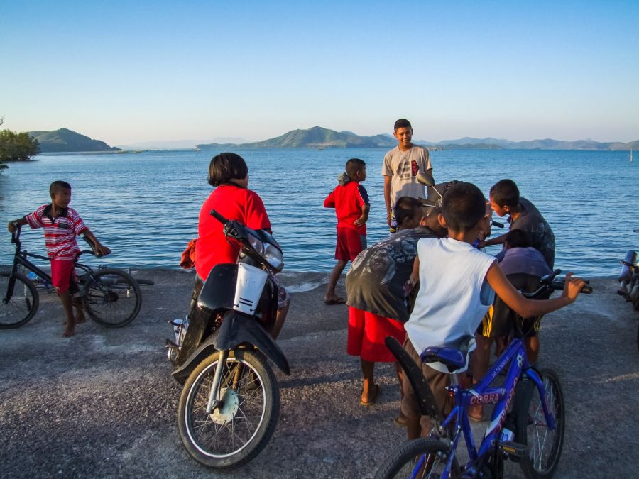 Enfants avec vélos et scooter au bord d’un lac
