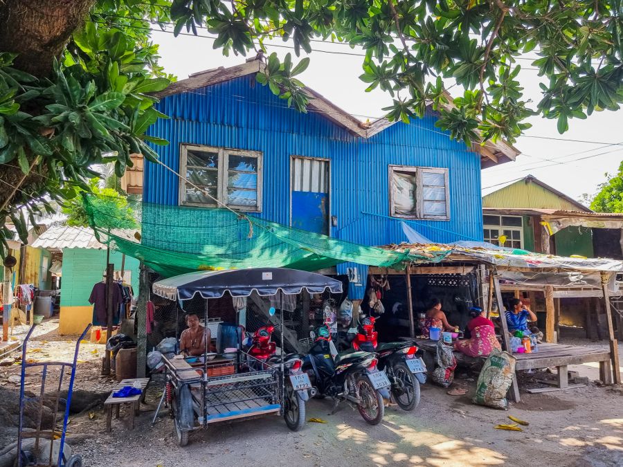 Maison bleue, motos et habitants sous des arbres