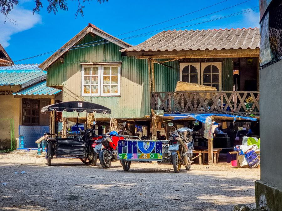 Maisons en bois et motos-taxis sous ciel bleu