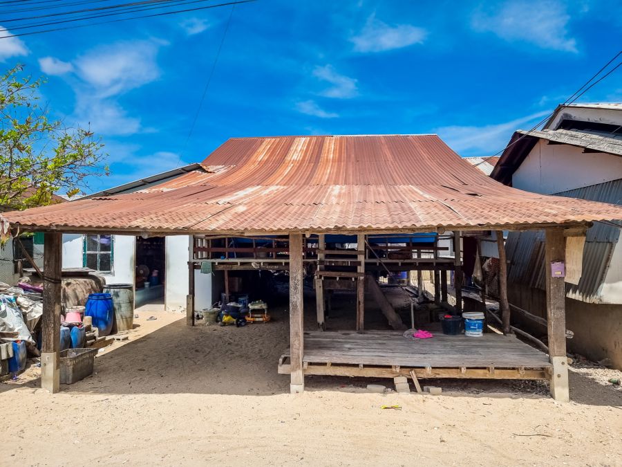 Maison sur pilotis au toit rouillé sous ciel bleu
