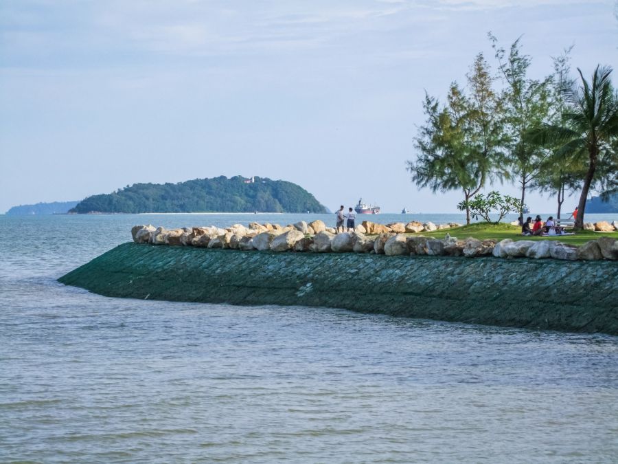 Promeneurs au bord de mer face à une île boisée