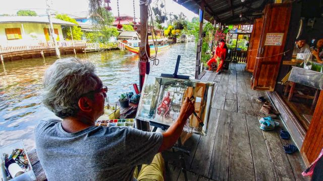 Artiste peignant un canal depuis une maison sur pilotis